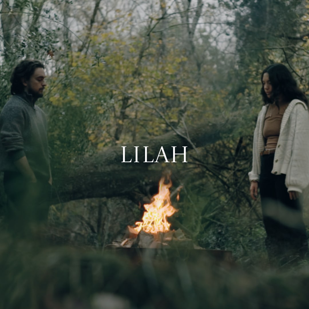 LILAH cover art — two figures facing each other across a campfire in damp woodland, the title set across the middle