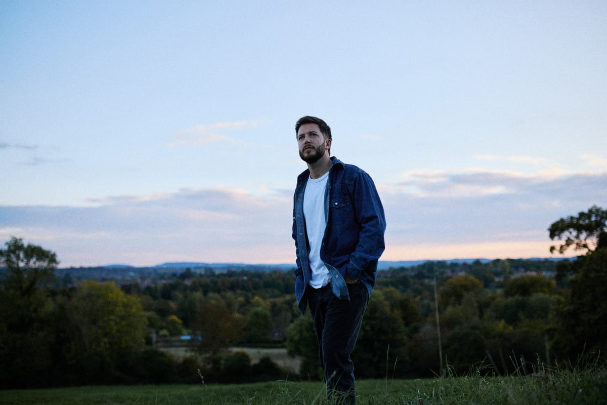 Josh Smith standing on a hillside above a valley at dusk
